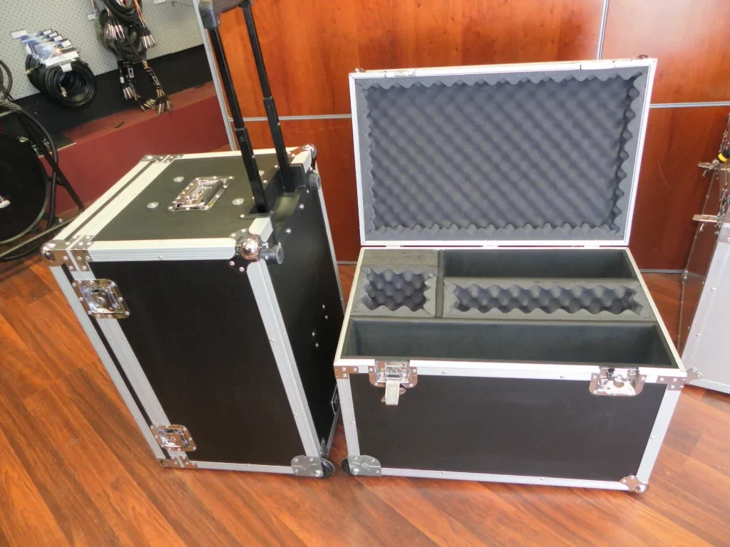 Two black flight cases, one with a telescopic trolley handle, the other open on compartmented foam