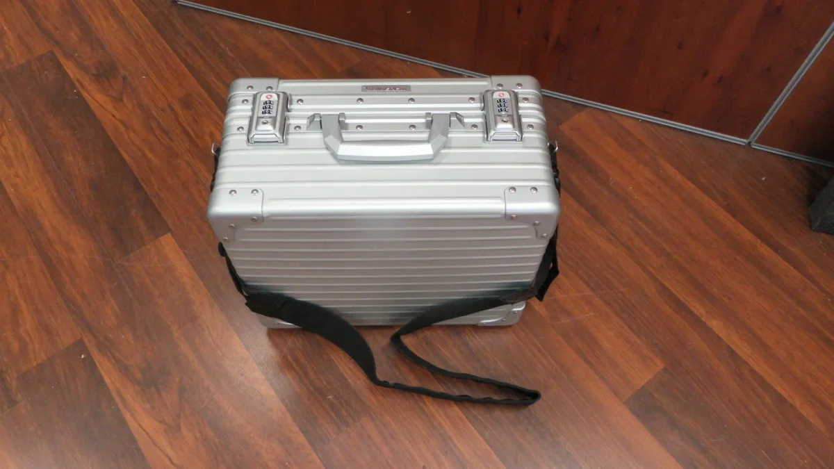Ribbed silver aluminium case with twin combination locks and a black shoulder strap