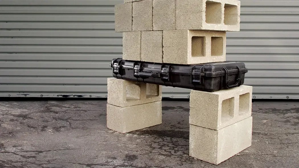 Black Pelican long case bridging two concrete block stacks under a load test