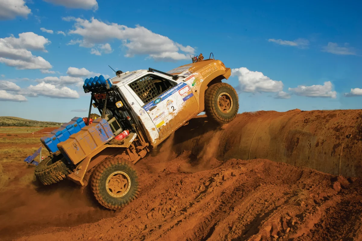 Off-road race truck cresting a red dirt bank with blue Spacecases mounted across the front