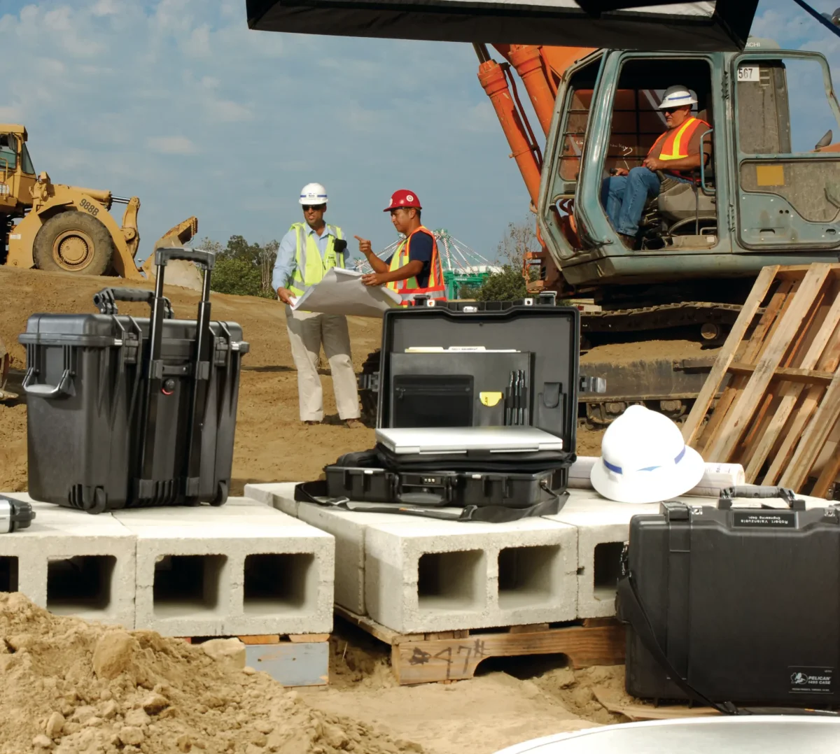 Construction site with Pelican cases on blockwork, one open around a laptop and site drawings