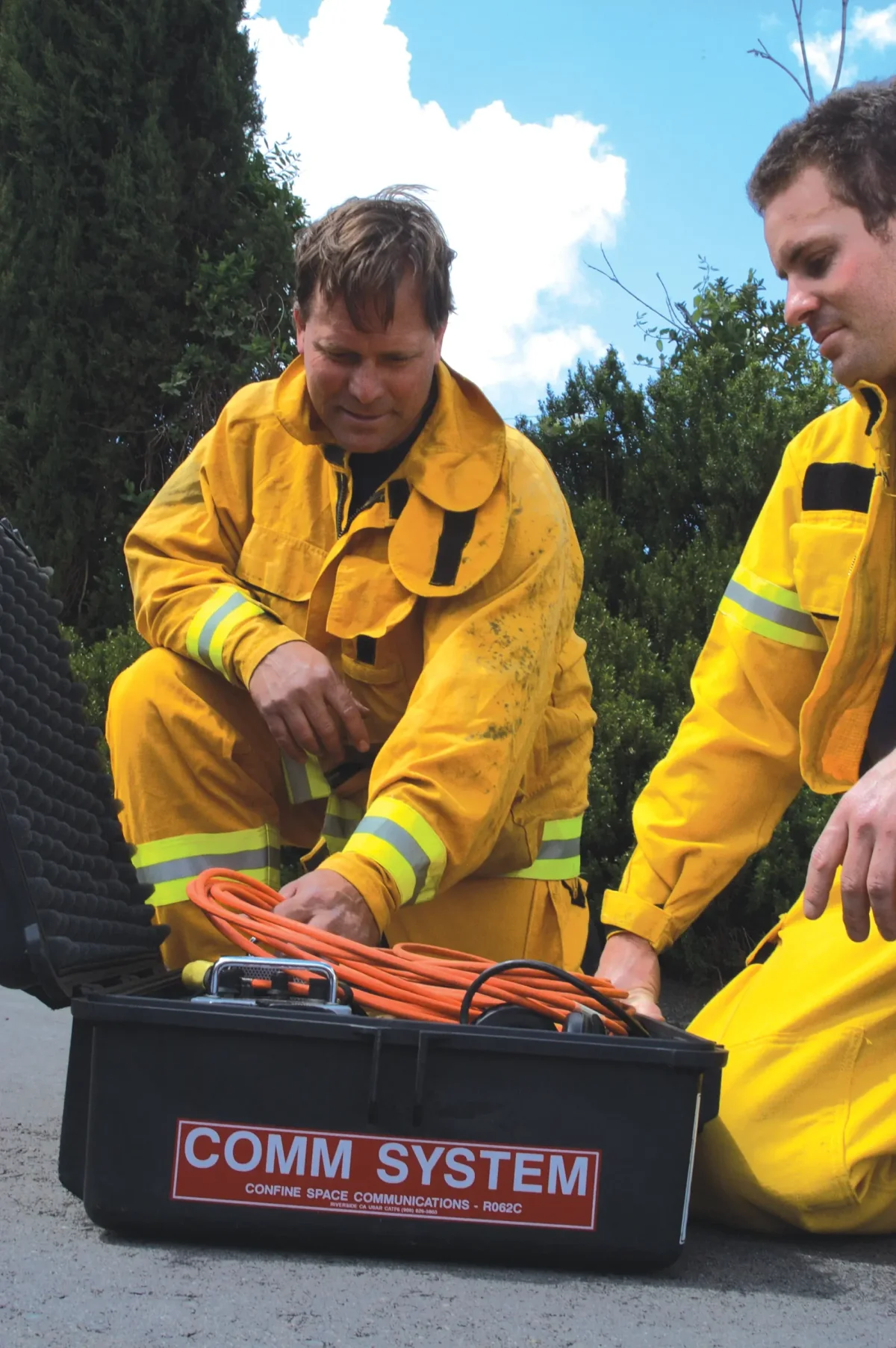 Firefighters uncoiling cable from a black Pelican case stencilled COMM SYSTEM