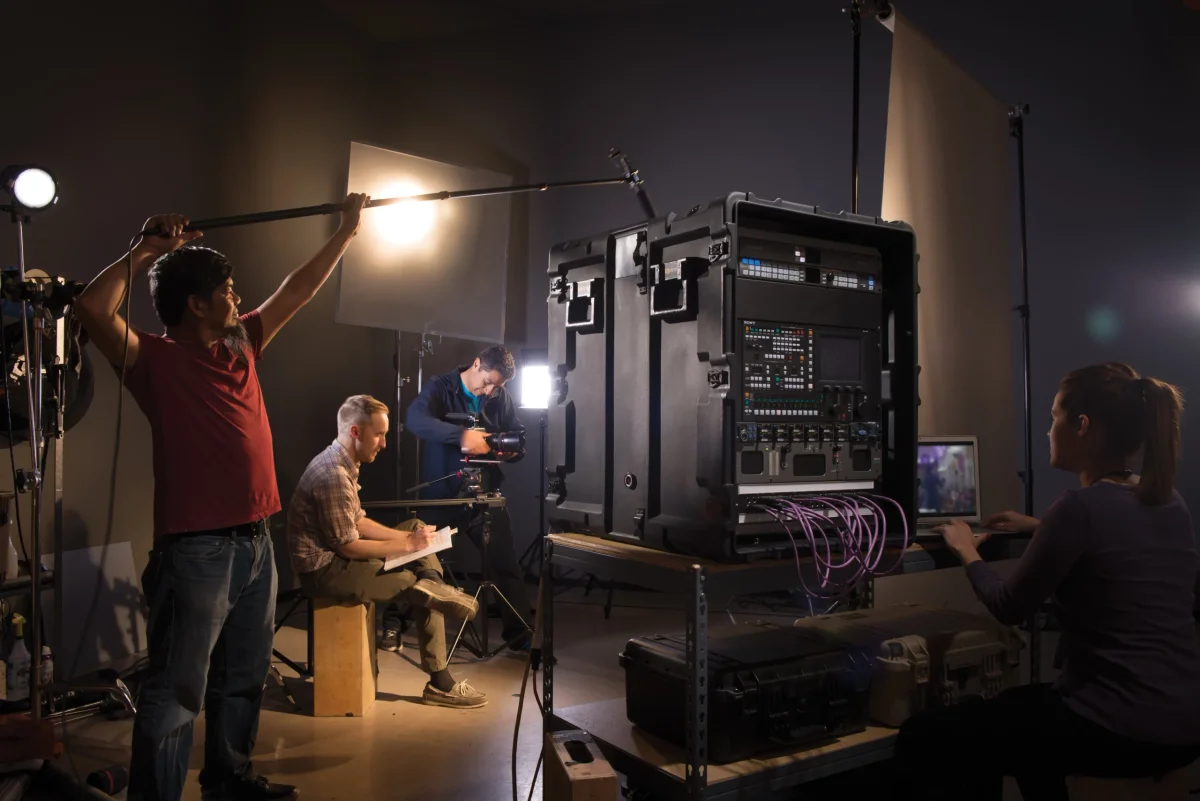 Film crew in a studio working from a large black Pelican-Hardigg rackmount case of broadcast gear