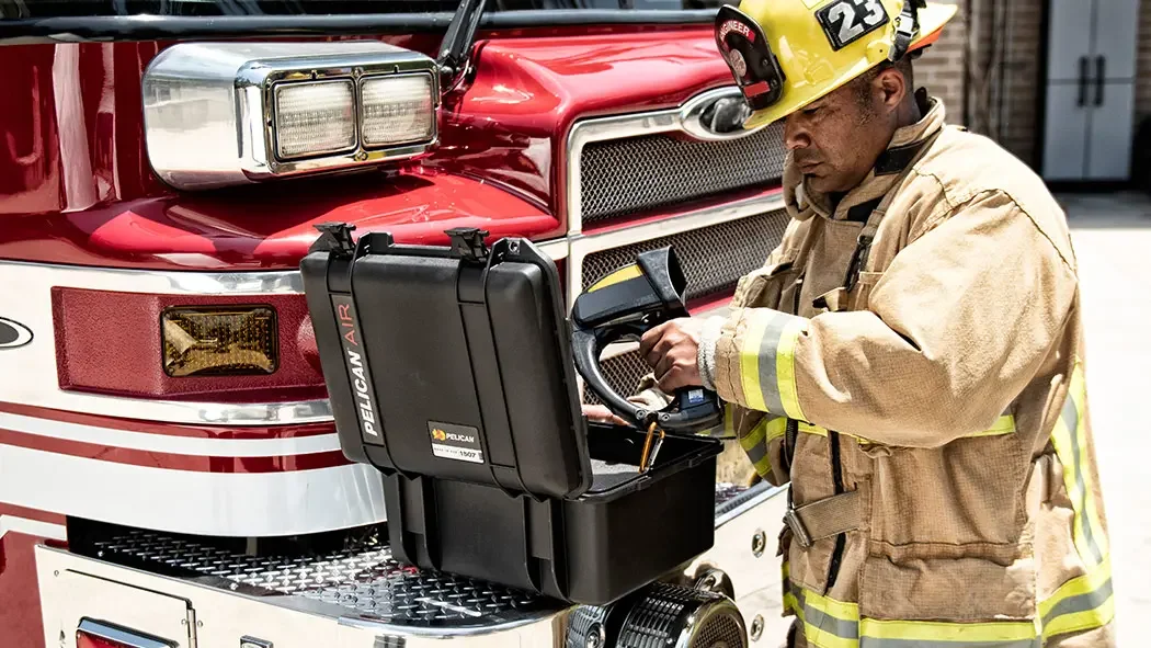 Firefighter lifting a thermal imaging camera from a Pelican Air case on the front of a fire truck