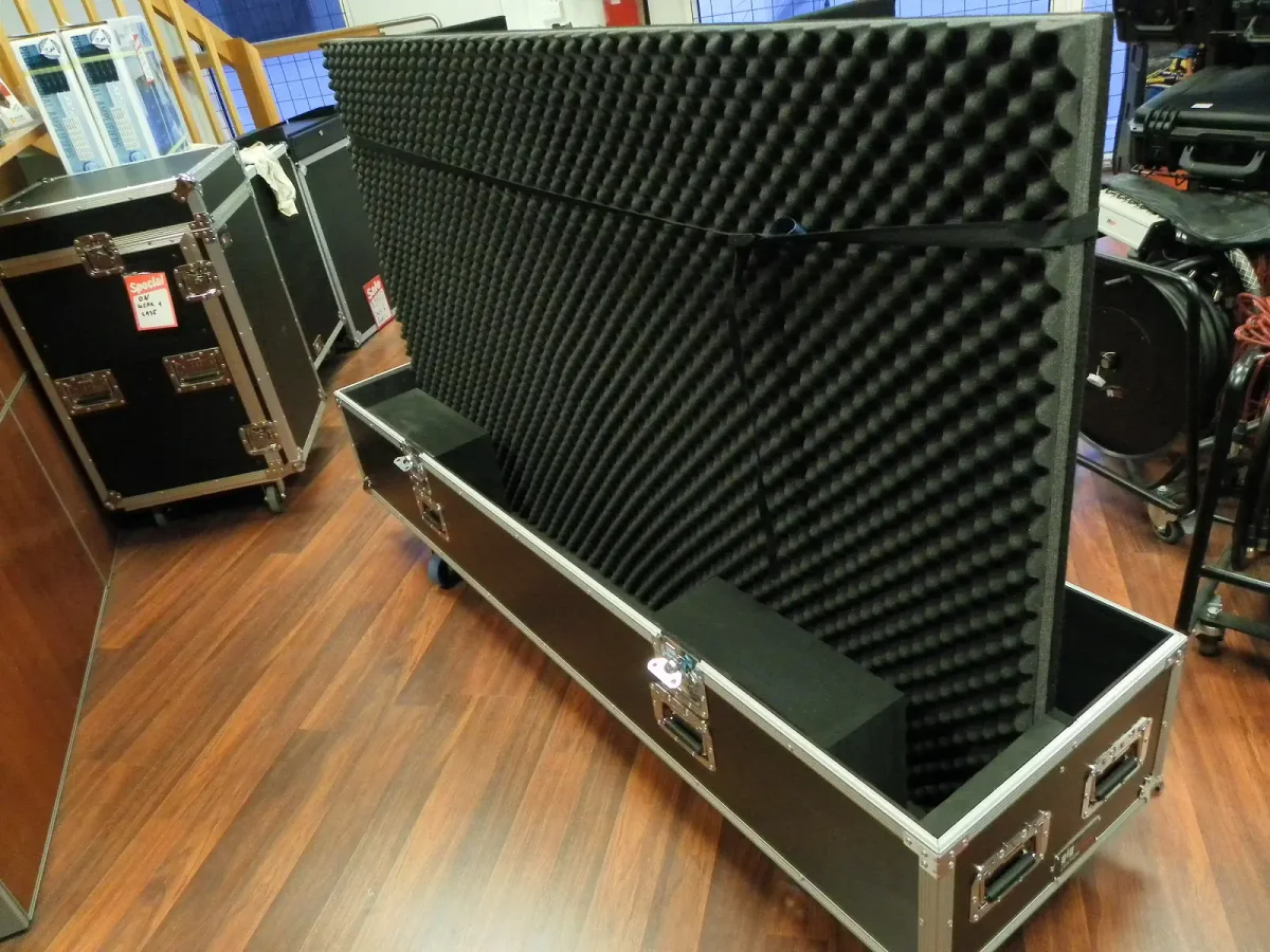 Long road case with a foam-lined lid propped open, cut to hold a flat panel