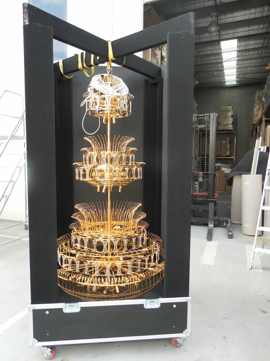 Road case opened into a black display frame with a gold chandelier suspended inside