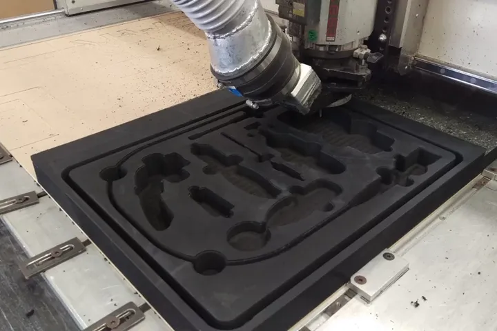 CNC router cutting a custom foam insert from black PE foam
