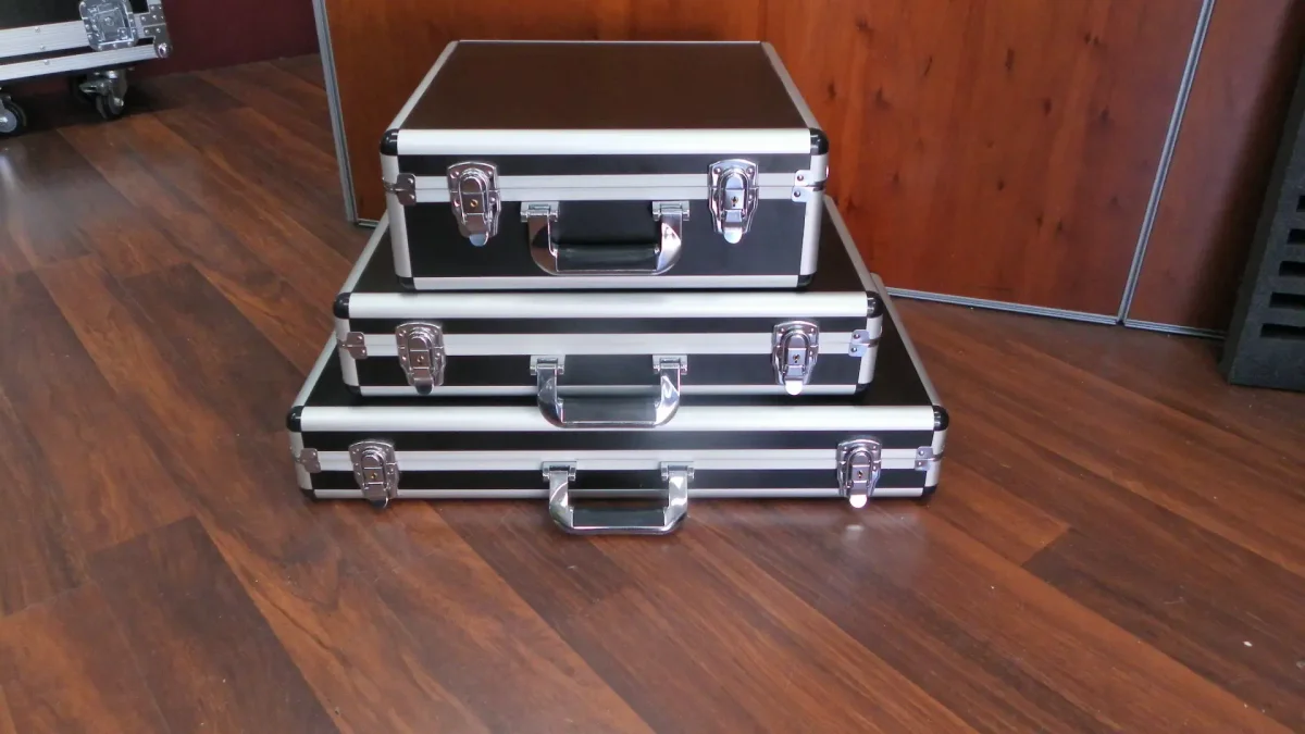 Three black aluminium tool briefcases in ascending sizes, stacked on a workshop floor
