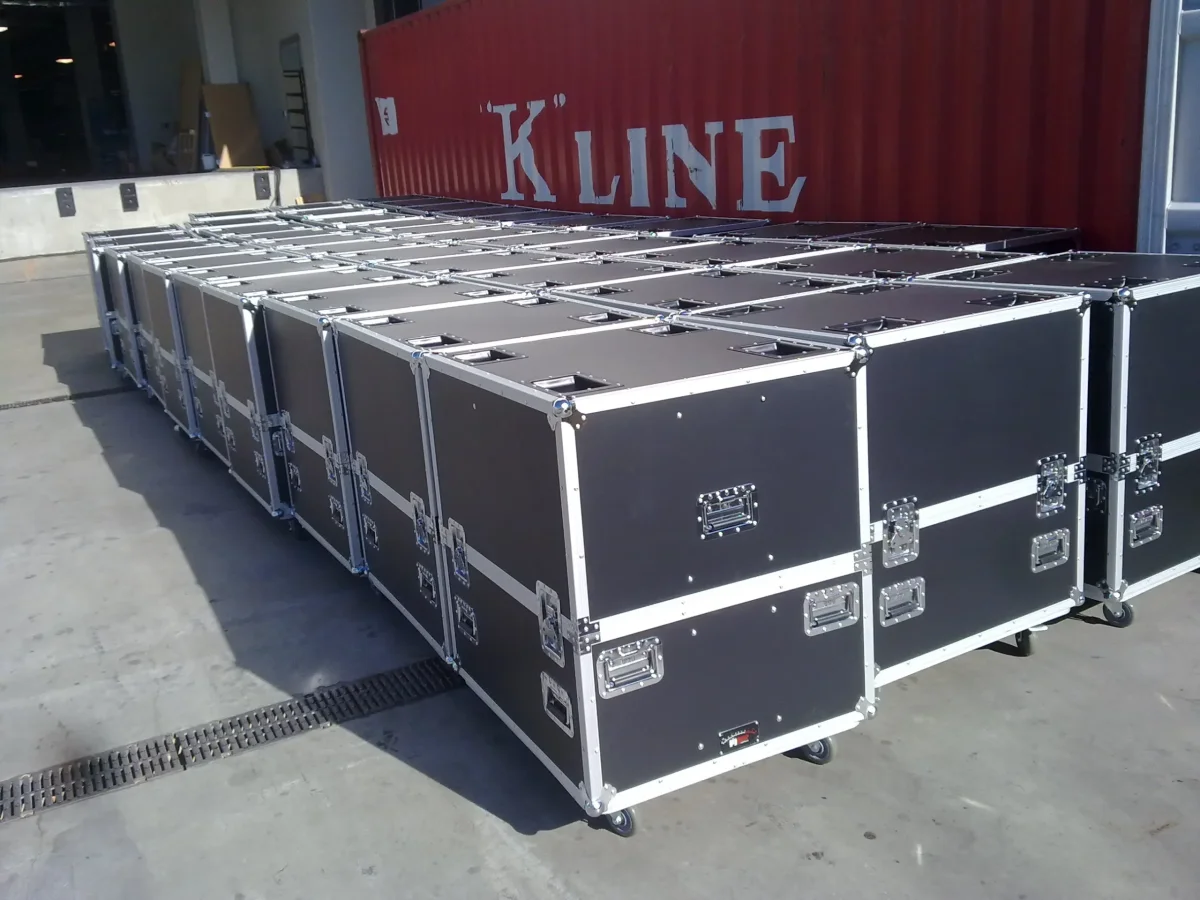 Rows of finished black road cases staged on the dock beside a shipping container