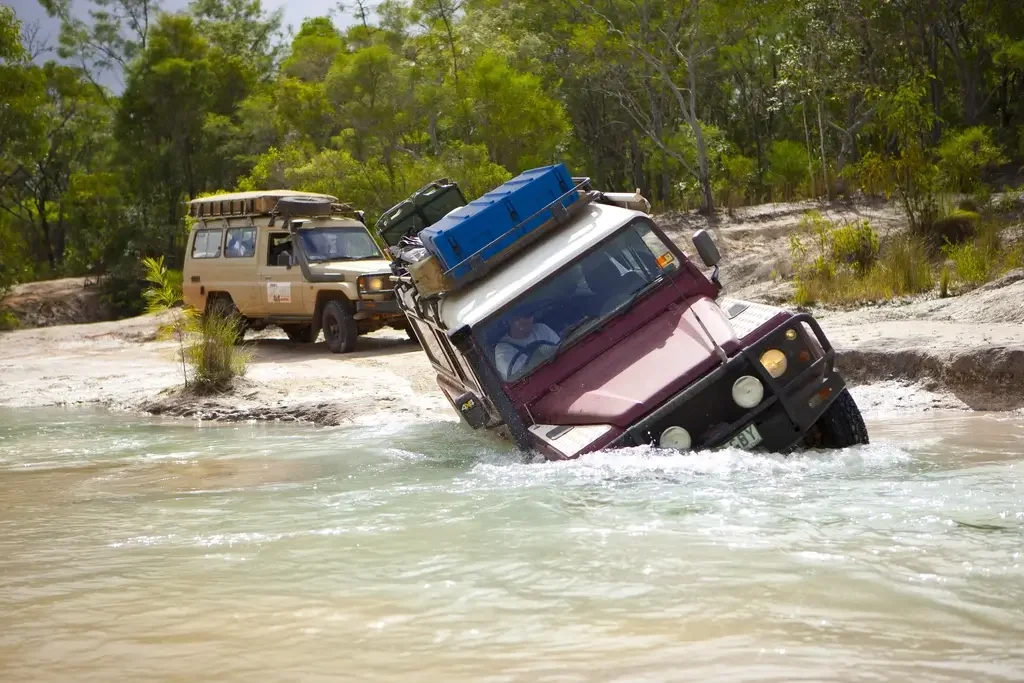 Four wheel drive fording a river crossing with a blue Pelican Spacecase on the roof rack